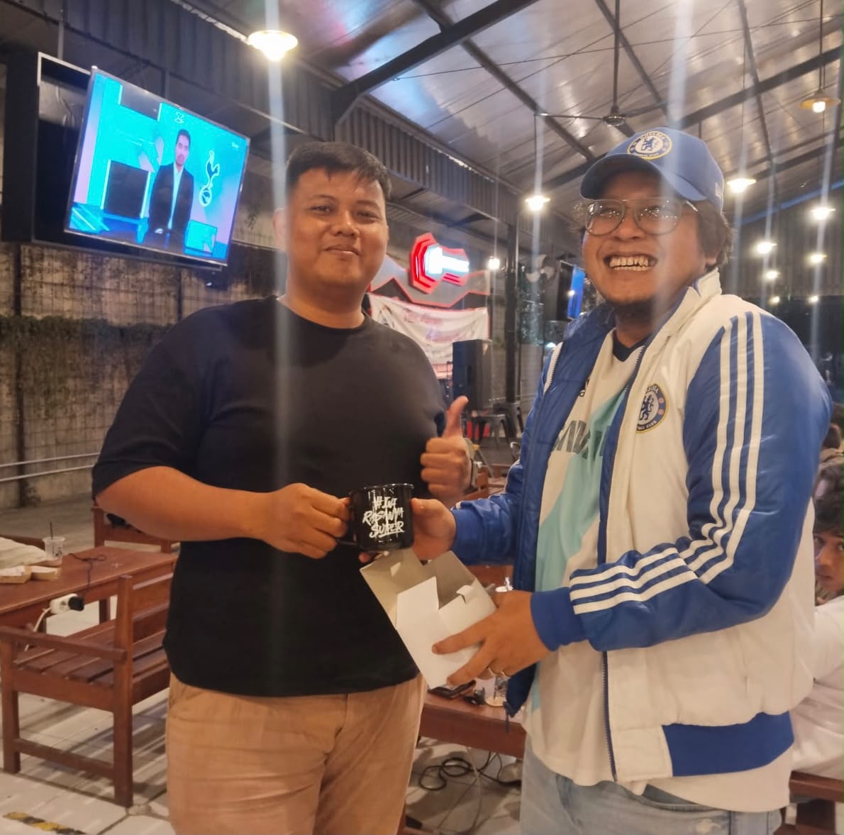 Dua peserta nobar berfoto dengan mug #TajRasanyaSuper.