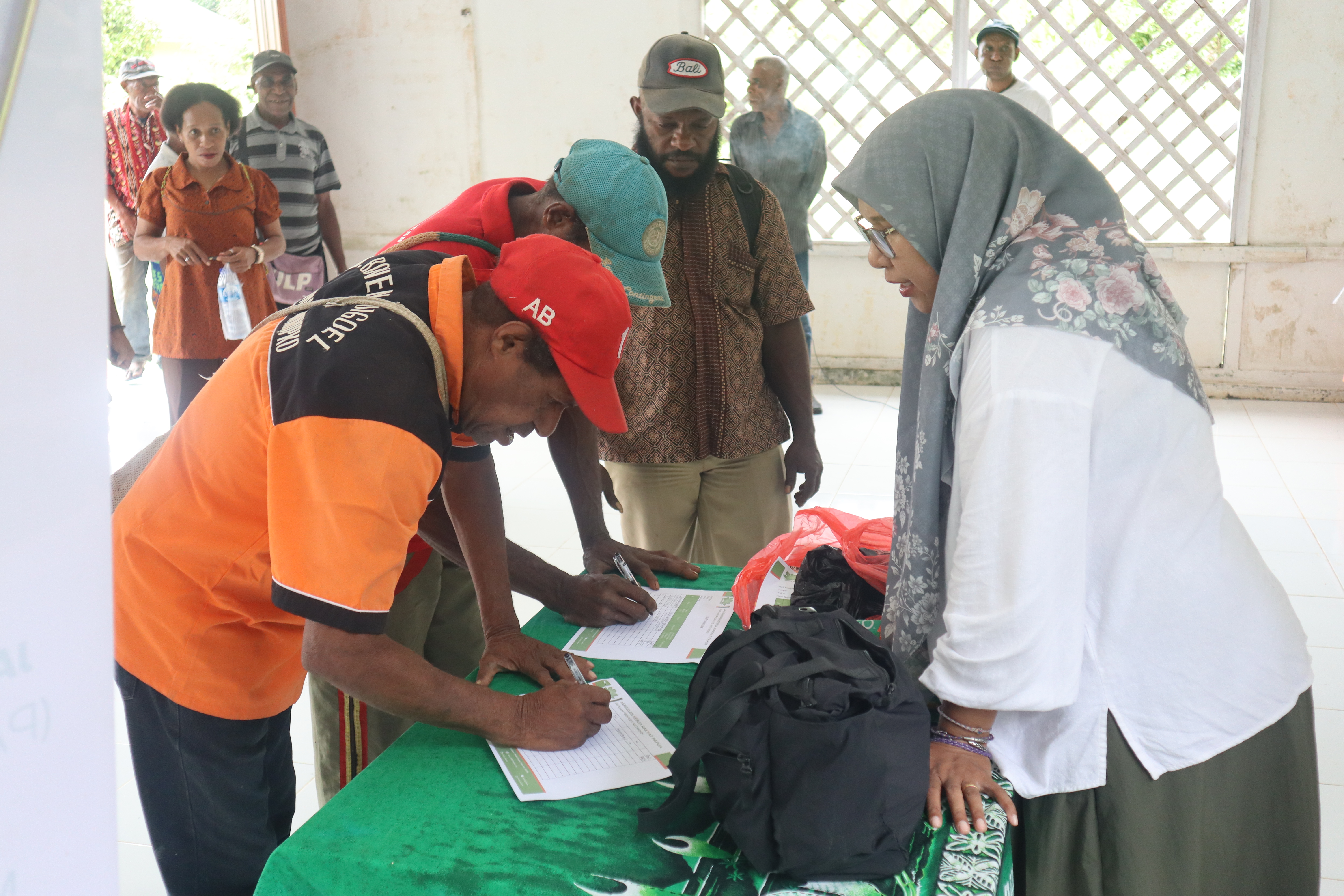 Peserta kegiatan Revitalisasi Kelembagaan Adat dan Penyusunan SOP Suku Muyu Kati melakukan registrasi sebelum mengikuti rangkaian kegiatan.
